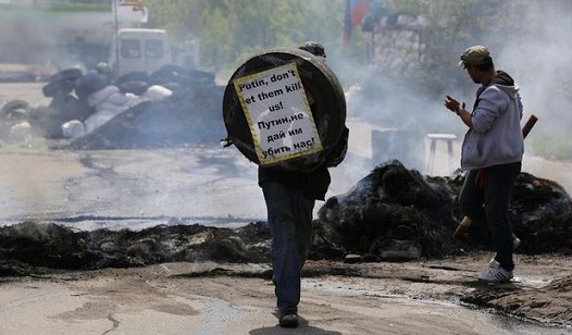 Un abitante locale filorusso di Kramatorsk tiene in mano uno pneumatico con un cartello che dice in inglese e in russo: "Putin non lasciare che ci uccidano!", 3 maggio 2014 (AP Photo/Max Vetrov)